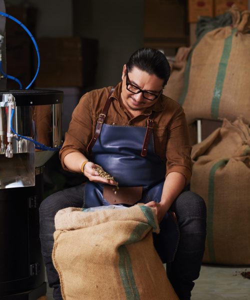 Vietnamese business owner checking if the coffee in sack is of a good quality